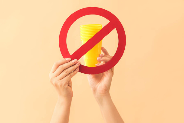 Female hands with plastic cups and stop sign on color background. Ecology concept - Фото, изображение