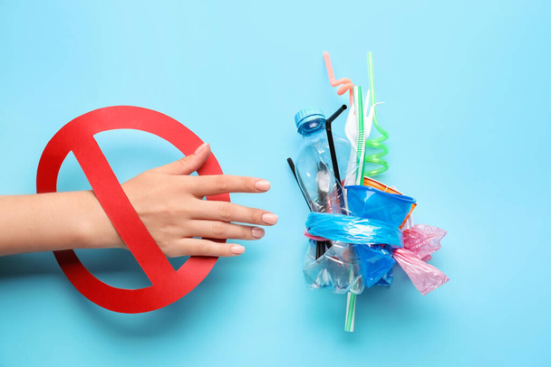 Female hand with plastic garbage and stop sign on color background. Ecology concept - Fotó, kép