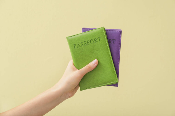 Main féminine avec passeports sur fond de couleur - Photo, image