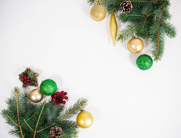 белый фон с яркими рождественскими украшениями и зелеными иглами праздничной елки - Фото, изображение