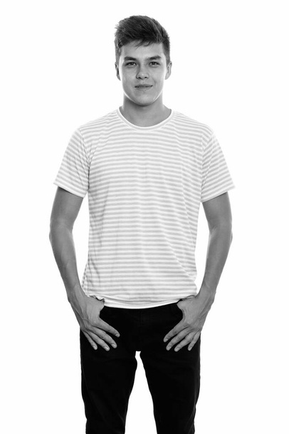 Studio shot of young handsome man isolated against white background in black and white - Fotografie, Obrázek