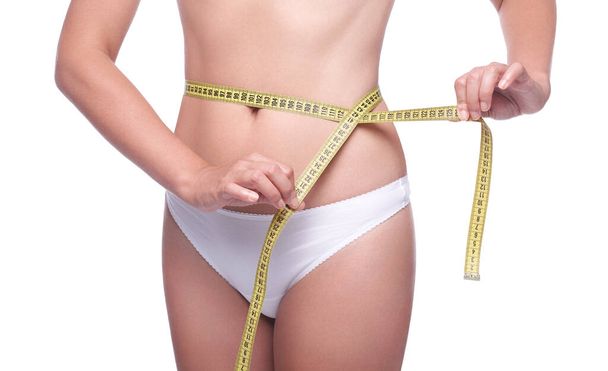 Ein schlankes Mädchen misst ihre Taille, Diät und Sporttraining, den Kampf gegen Cellulite, eine junge Frau in Unterwäsche, Gesundheits- und Körperpflege, auf weißem Hintergrund - Foto, Bild