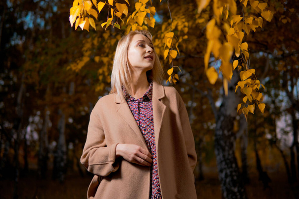 Молода красива жінка в довгому пальто в осінньому лісі. концепція осені
. - Фото, зображення