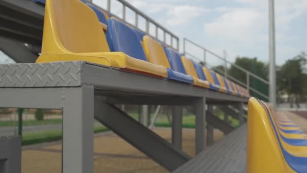 4k, tyhjät muoviset istuimet stadionilla. Keltaiset ja siniset istuimet jalkapallostadionilla Tribune ilman katsojia ja faneja - Materiaali, video