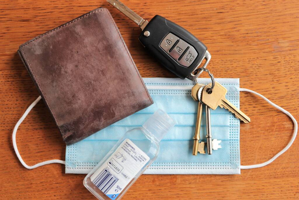 Укладка ключей от машины, коричневого кожаного бумажника, маски для лица и геля для дезинфекции рук - Фото, изображение