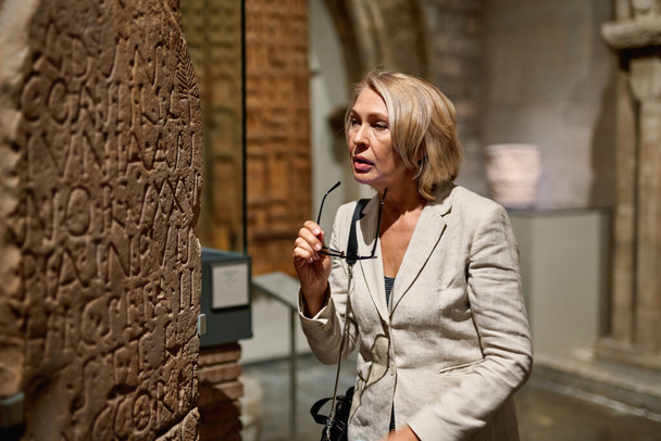 Зріла жінка відвідує античний музей
 - Фото, зображення