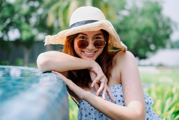 Крупним планом портрет красива азіатка мандрівник з сонцезахисними окулярами і капелюхом біля басейну
. - Фото, зображення
