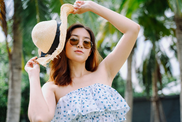 Retrato de hermosa mujer asiática viajero con gafas de sol y sombrero en el resort al aire libre. - Foto, imagen