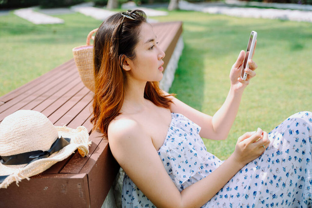 公園で屋外スマートフォンを使用して美しいアジアの女性旅行者. - 写真・画像
