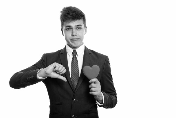 Studio shot of young handsome businessman in suit isolated against white background in black and white - Photo, Image