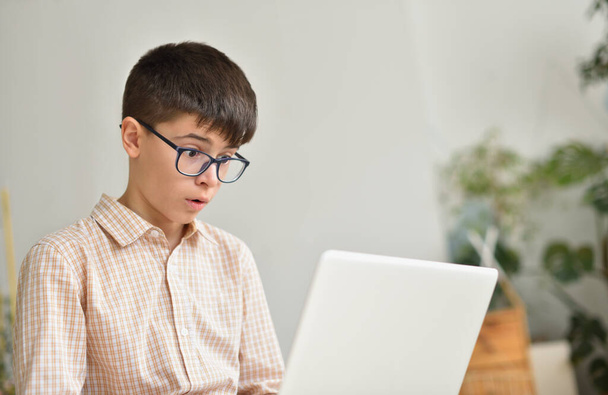 Caucasian white teenager boy looking in surprise at laptop - Photo, Image