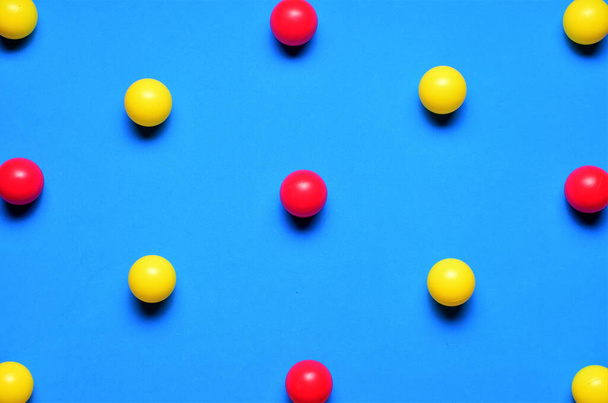 Small colored balls, red and yellow, on a blue background, placed in line, space for text - Foto, Imagem
