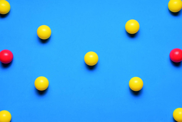 Pequeñas bolas de colores, amarillo y rojo, sobre un fondo azul, colocadas en línea, espacio para el texto - Foto, imagen