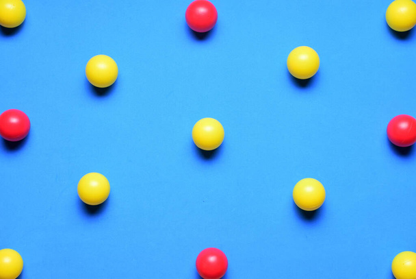 Pequenas bolas coloridas, amarelo e vermelho, sobre um fundo azul, colocado em linha, espaço para texto - Foto, Imagem