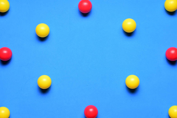 Small colored balls, yellow and red, on a blue background, space for text in the center - Photo, image