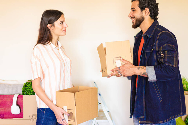 Boldog fiatal pár költözik az új ingatlanházba. A boldog érzésű munkások dobozokat tartanak az új irodában. Bérlés, vásárlás lakás és életmód koncepció. - Fotó, kép