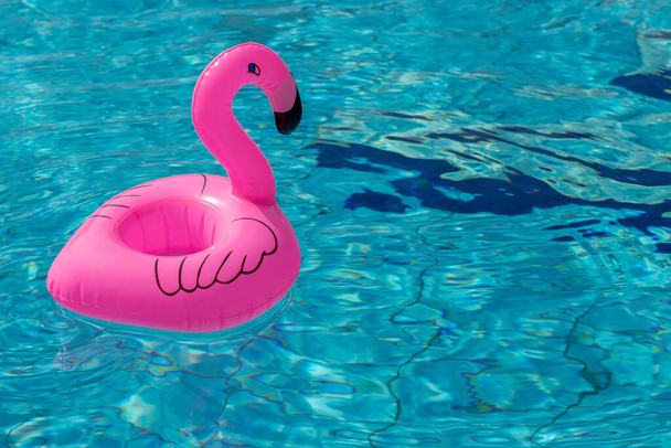 Sommerferienposter. Rosa aufblasbare Flamingo im Pool Wasser für Sommer Strand Hintergrund. Lustiges Vogelspielzeug für Kinder - Foto, Bild
