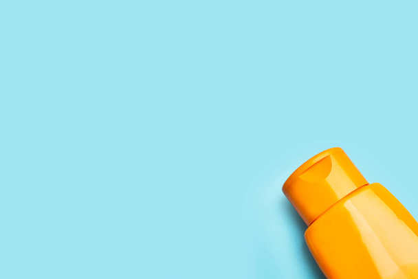 An plastic orange suntan lotion bottle on a light blue background with copy space - Photo, Image