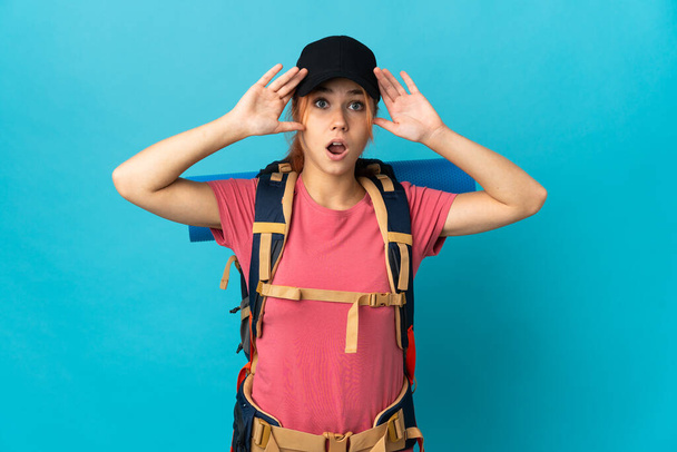 Teenager Russian hiker girl isolated on blue background with surprise expression - Fotoğraf, Görsel