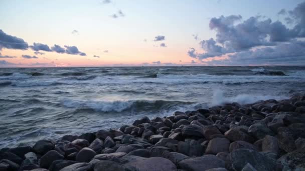 De zeegolf crasht ook tegen het rotsachtige strand bij zonsondergang. Zeegezicht. - Video