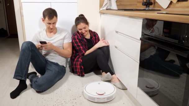 Family controls robot vacuum cleaner operation with phone - Footage, Video