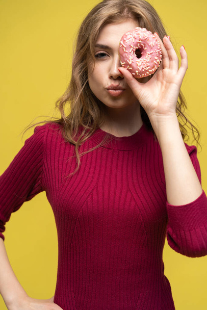 Woman covering her eyes with donut over yellow donut. - Photo, image