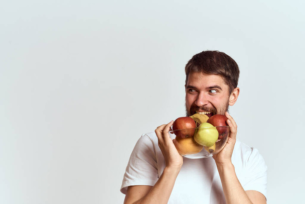 Mann mit frischem Obst in einer Glasschale gestikuliert mit den Händen Vitamine Gesundheit Energie Modell buschiger Bart Schnurrbart - Foto, Bild