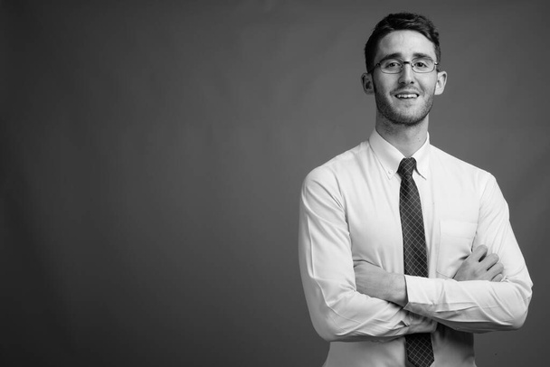 Студійний знімок молодого гарного бізнесмена в окулярах на сірому фоні в чорно-білому
 - Фото, зображення