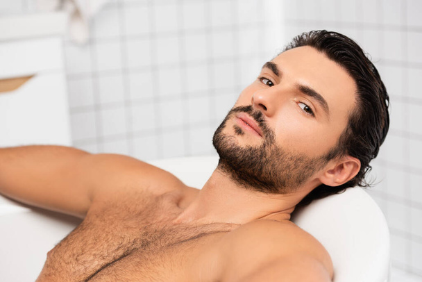 Bearded man looking at camera while taking bath  - Фото, зображення