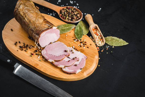 Tasty smoked ham with spices on black background. Copy space - Foto, imagen