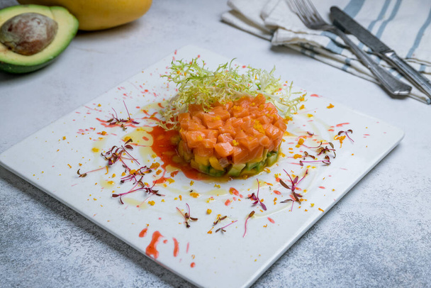 salmon Tartar with avocado on a white plate - 写真・画像
