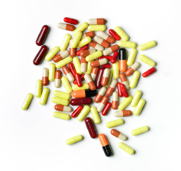 Bovenaanzicht van stapel van kleurrijke pillen tegen witte achtergrond. - Foto, afbeelding