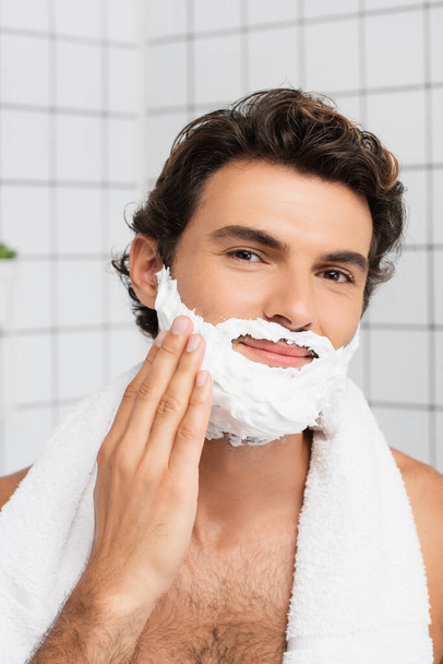 Smiling man looking at camera while applying shaving foam  - Zdjęcie, obraz