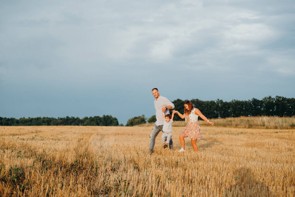 Happy family playing on the grass in the field in the evening. - Foto, immagini