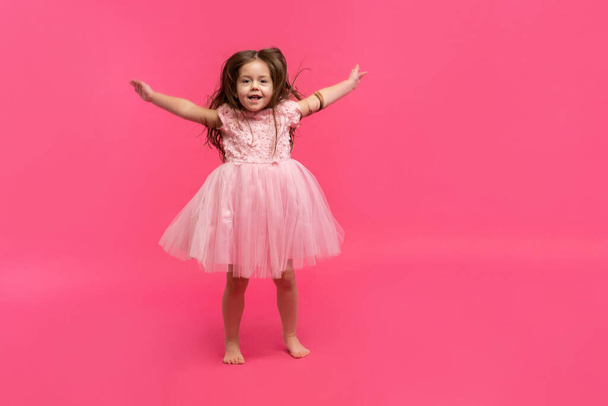 Cute little girl dreams of becoming a ballerina. Little Dancing Girl. Studio Shoot Over Pink Background - Foto, Imagem