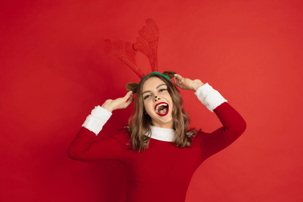 Beautiful woman like Christmas deer isolated on red background. Concept of 2021 New Years, winter mood, holidays. - Zdjęcie, obraz