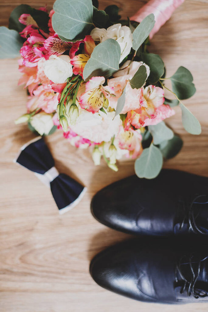 Groom shoes with wedding bouquet on wooden background - Fotó, kép