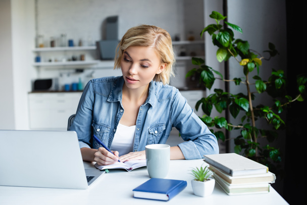 young blonde woman studying online and making notes - Foto, Imagem