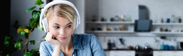 young blonde woman in headphones leaning on hand and looking down, banner - Photo, Image