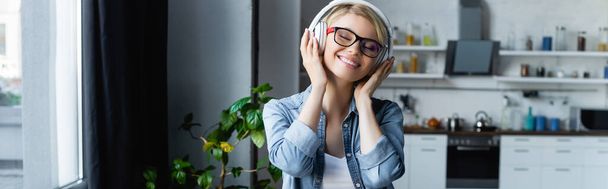 young blonde woman in eyeglasses listening music, horizontal banner - 写真・画像