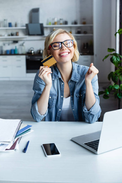 happy blonde woman in eyeglasses making purchase online - Foto, imagen