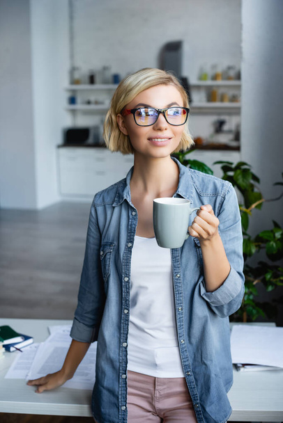 young blonde woman in eyeglasses drinking tea at home - Photo, Image