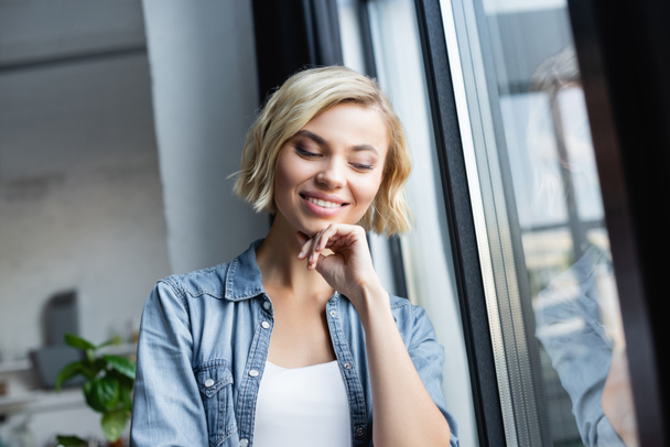 portré mosolygós nő áll ablak mellett - Fotó, kép