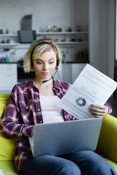 young blonde woman in headphones having online conference and showing graphs - Foto, afbeelding