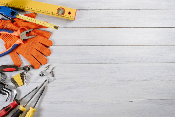 Různé stavební nebo řemeslné nástroje a rukavice ploché na bílém dřevěném pozadí - Fotografie, Obrázek