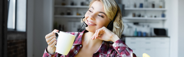 young blonde woman in checkered shirt and headphones drinking tea, banner - Foto, afbeelding