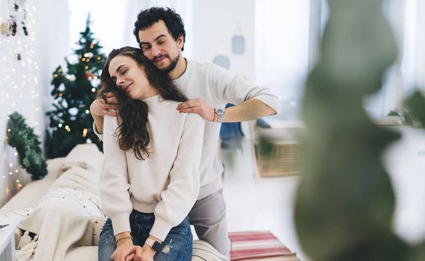 Young caucasian romantic couple in love enjoying spending time on winter vacations at home together, handsome tender male enjoying resting at apartment with girlfriend on weekend celebration - Foto, afbeelding