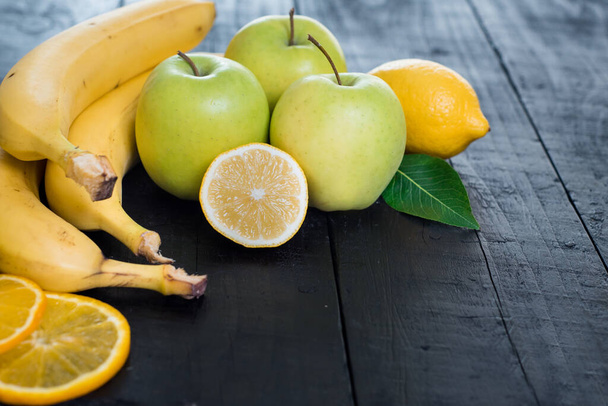 Apples, bananas and lemon on black background - Fotó, kép