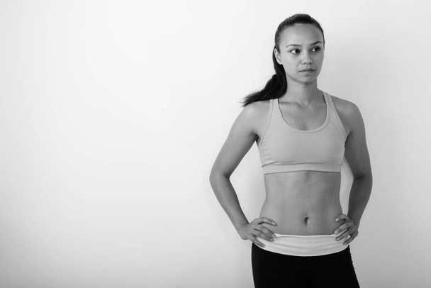 Studioaufnahme einer jungen schönen Asiatin, bereit für das Fitnessstudio vor weißem Hintergrund in schwarz-weiß - Foto, Bild