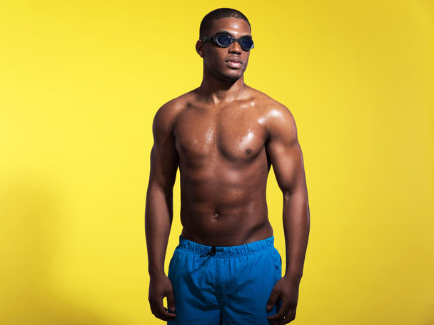 Athletic swimmer with waterdrops. Black man wearing blue swimmin - Фото, зображення